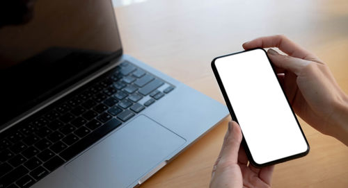 Low section of person holding smart phone on table