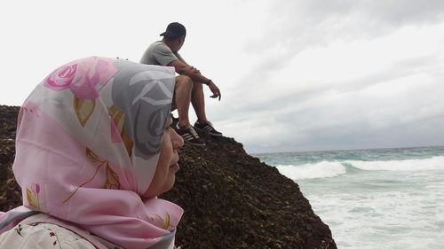 People at beach against cloudy sky