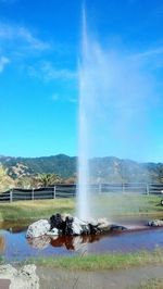 Water splashing on fountain against blue sky