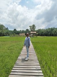 Full length of man standing on grassy field against sky