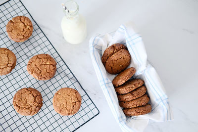 Freshly baked healthy vegan cookie on a cooling rack stand on a table next to milk. view from