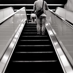 Rear view of man on escalator with head cut off