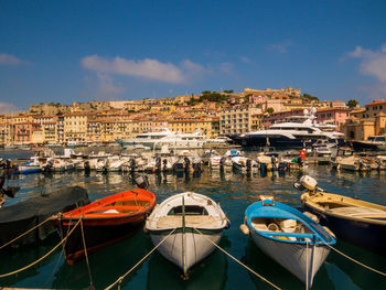 High angle view of boats moored at harbor by buildings in city