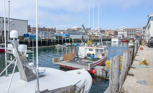 Sailboats moored at harbor against sky in city