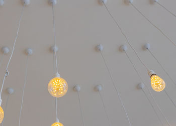 Low angle view of illuminated light bulbs hanging from ceiling