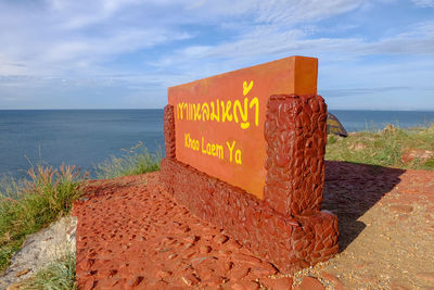 Information sign on beach against sky