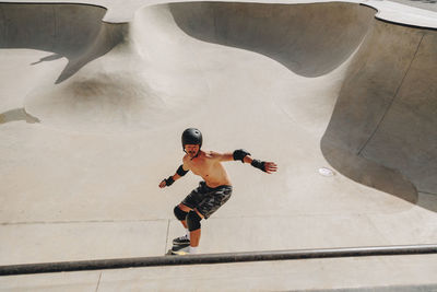 Man wearing crash helmet skateboarding on ramp