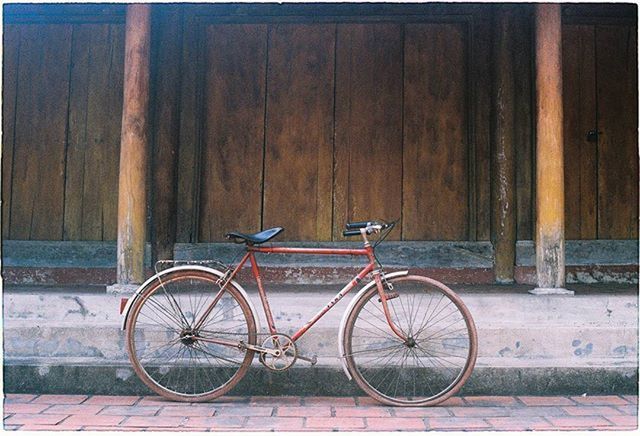 bicycle, mode of transport, transportation, stationary, land vehicle, parking, parked, wall - building feature, wheel, wood - material, built structure, leaning, architecture, cycle, day, no people, outdoors, building exterior, sidewalk, door