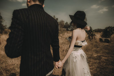 Rear view of couple holding hands against sky