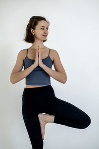 Portrait of young woman standing against white background