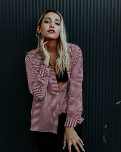 Portrait of young woman standing against wall