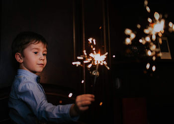 Portrait of boy looking at illuminated christmas lights at night