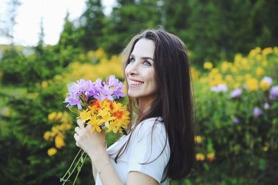 Portrait of beautiful woman against white flowering plants