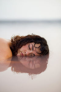 Portrait of shirtless young woman swimming in sea