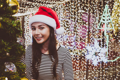 Portrait of smiling young woman standing by christmas