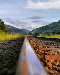 Railroad track by mountain against sky