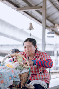 Mature woman putting food packages in wicker basket