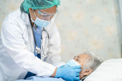 Doctor examining patient lying on bed in hospital