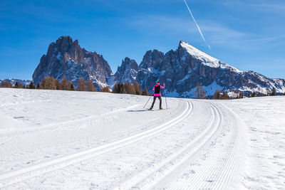 Woman skiing on snowy land against snowcapped mountains