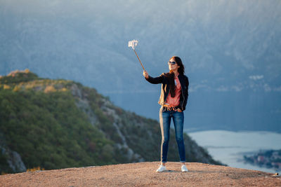 Woman taking selfie while standing against mountains