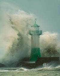 Lighthouse by sea against sky