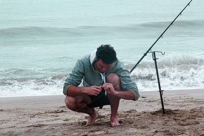 Full length of man sitting on shore at beach