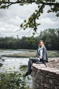 Portrait of woman sitting on retaining wall