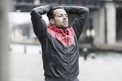 Sporty tired man with hands behind head outdoors