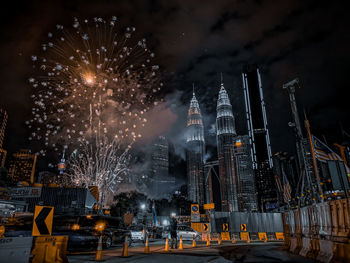 Firework display in city against sky at night