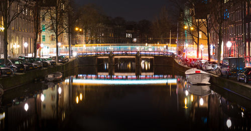 Illuminated bridge over canal in city at night