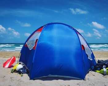 Tent on beach against blue sky