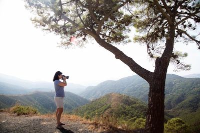 Woman photographing through smart phone on landscape