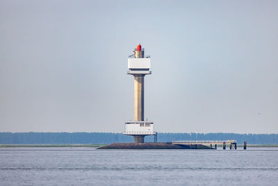 Lighthouse by sea against sky