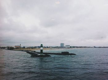 Boats in river against cloudy sky