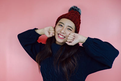 Portrait of smiling young woman against pink background