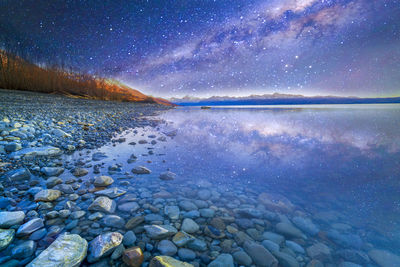 Scenic view of lake against sky at night