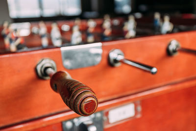 Closeup of weathered wooden handle of retro coin operated tabletop soccer game in recreation room