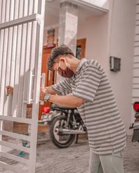 Side view of man wearing mask holding gate