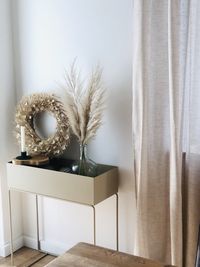 Flower vase and wreath kept on table at home