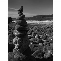 Stack of pebbles on beach against sky