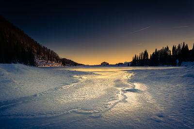 Scenic view of snow covered land during sunset