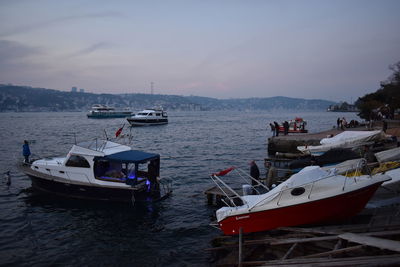 Boats moored in the sea against the sky during sunset