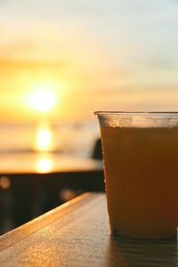 Close-up of water in glass on table against sky during sunset