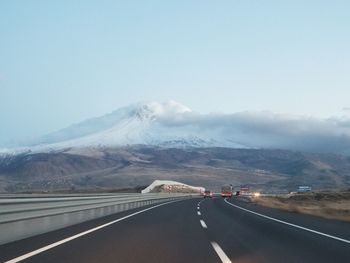 Road leading towards mountains against sky