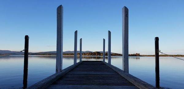 Wooden pier on lake against clear sky