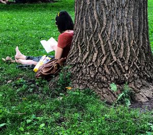 Boy sitting on tree trunk