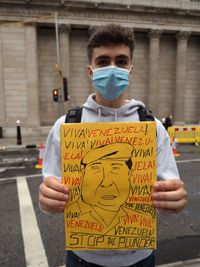 Portrait of young man standing on street in city