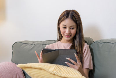 Portrait of young woman sitting on sofa at home