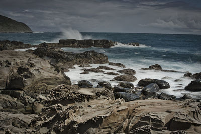 Scenic view of rocks in sea against sky