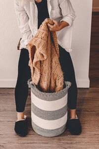 Low section of woman removing sweater from bag in home